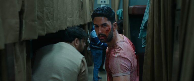 Lakshya as Amrit, bloodied and tense, crouches in a dim train corridor during a brutal fight scene in the Hindi action thriller Kill (2024).