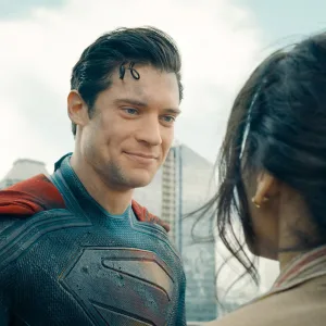 Superman smiles reassuringly at a citizen after a rescue on a Metropolis rooftop.