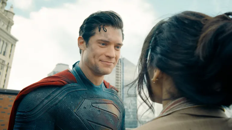 Superman smiles reassuringly at a citizen after a rescue on a Metropolis rooftop.