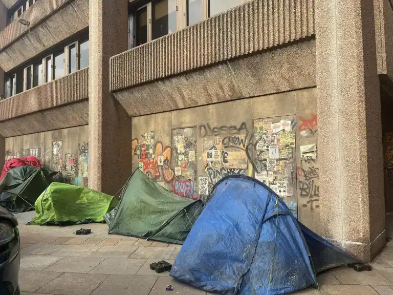 Tents and graffiti outside a building in Liverpool, dressed as Gotham City for filming of DC Studios’ Clayface movie.