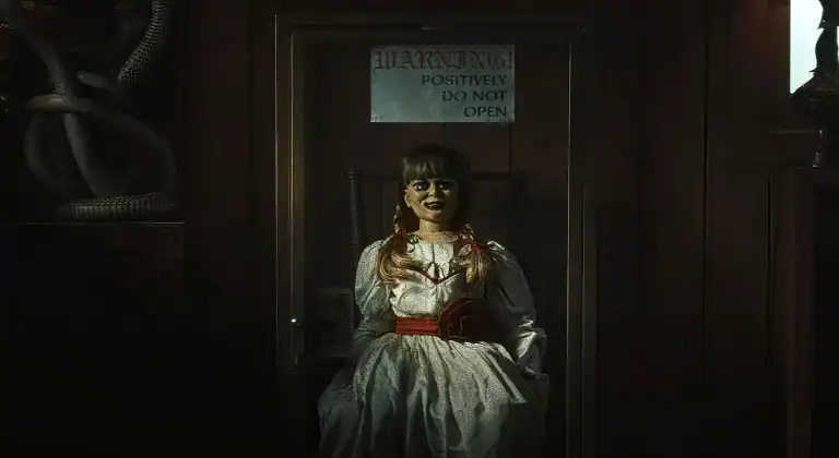 The Annabelle doll sits ominously inside a glass case with a warning sign reading “Positively Do Not Open” in The Conjuring: Last Rites.