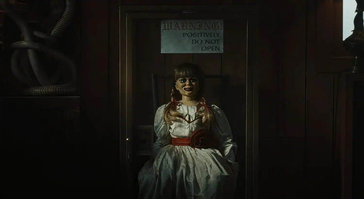 Annabelle doll locked inside a glass case with a warning sign reading “Positively Do Not Open” in The Conjuring: Last Rites review.