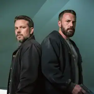 Back-to-back detectives in a teal, low-ceilinged room, one holding a pistol at waist height—moody, cinematic look for Netflix’s The Rip.